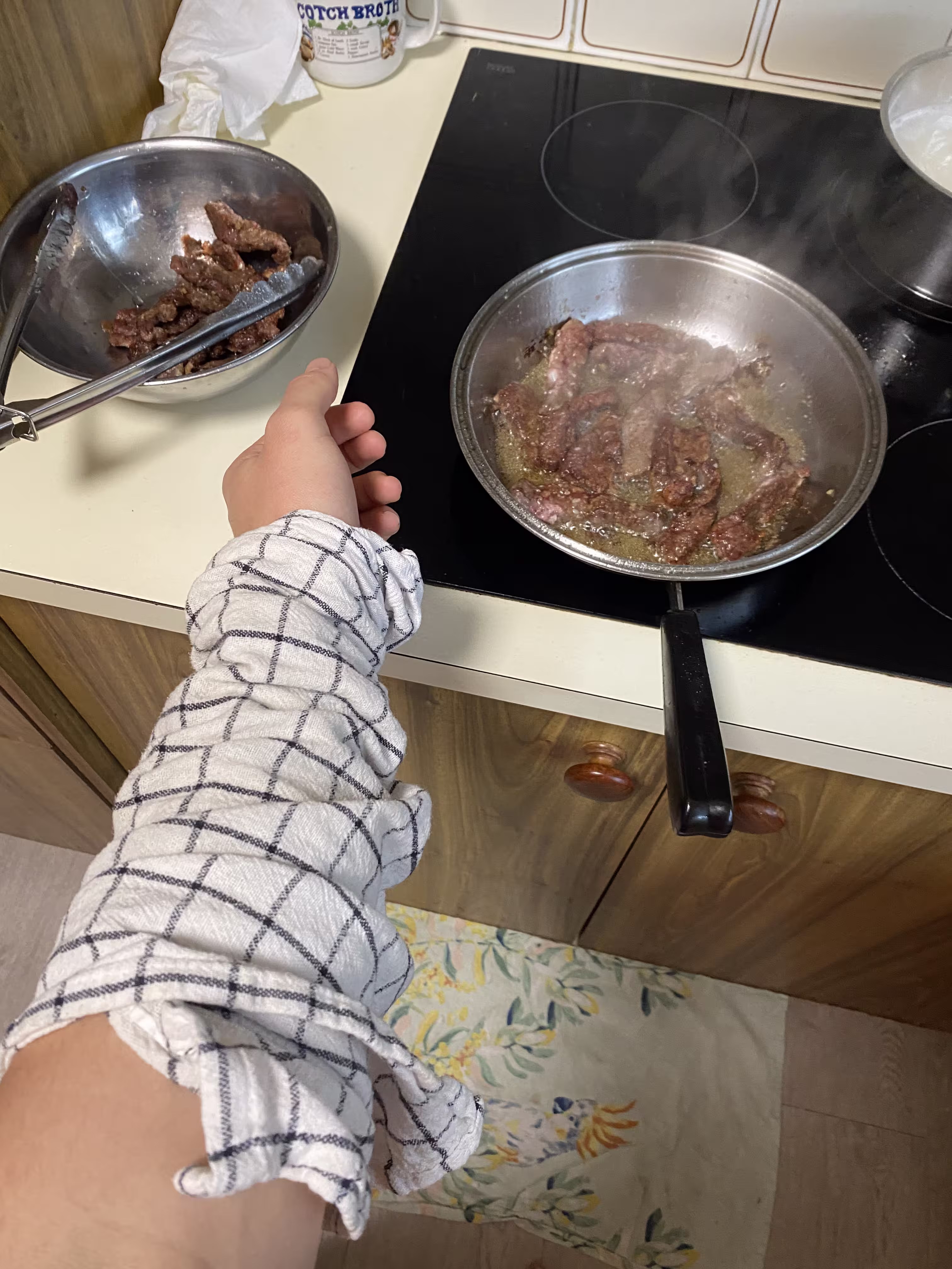Floor and arm covered in teatowel to protect from sizzling beef